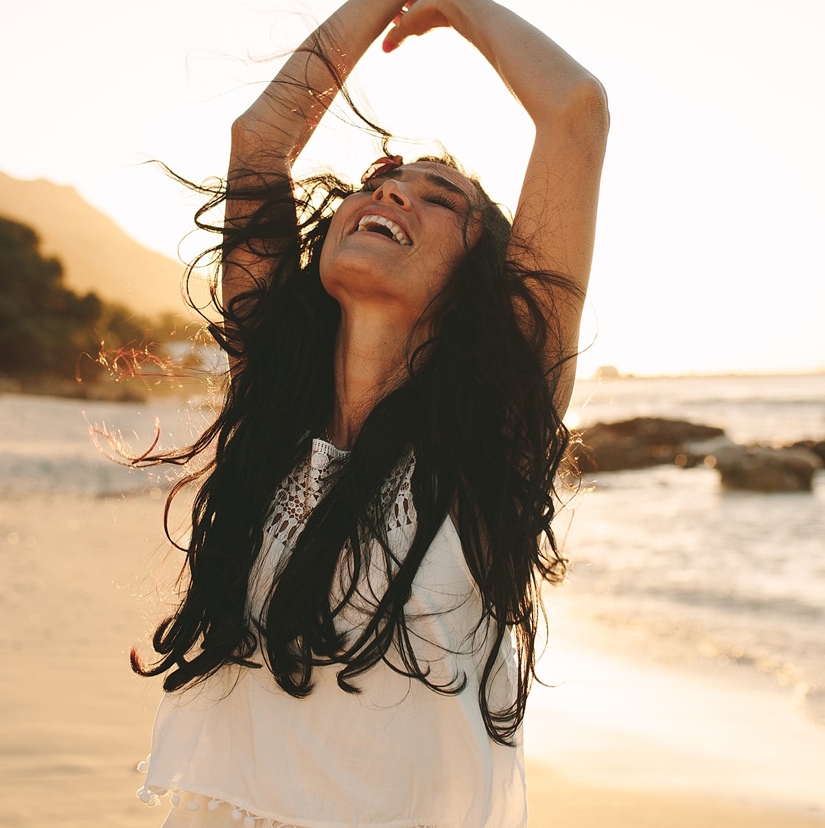 Woman celebrating joyfully at the beach.