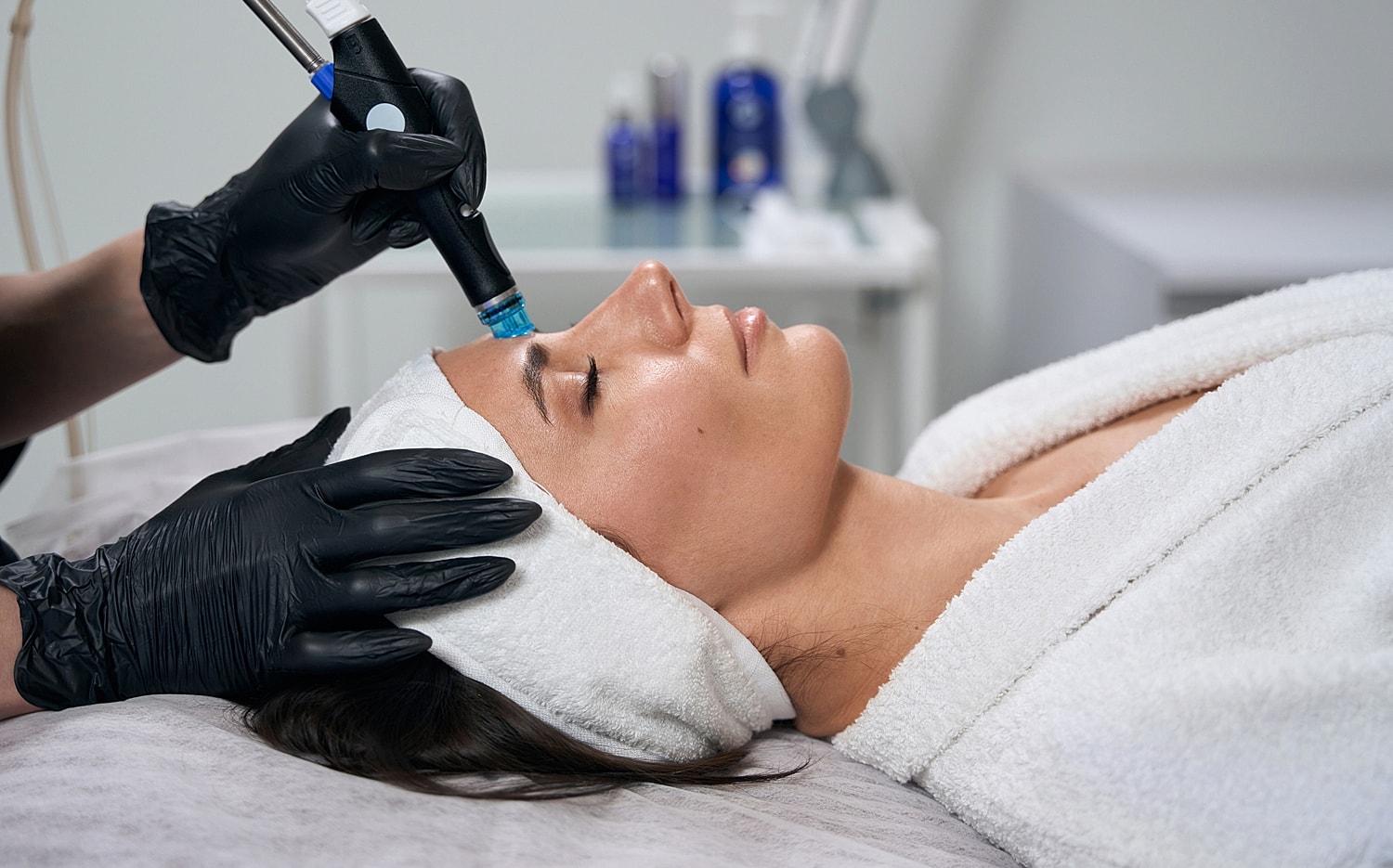 Woman receiving a facial treatment with microneedling.