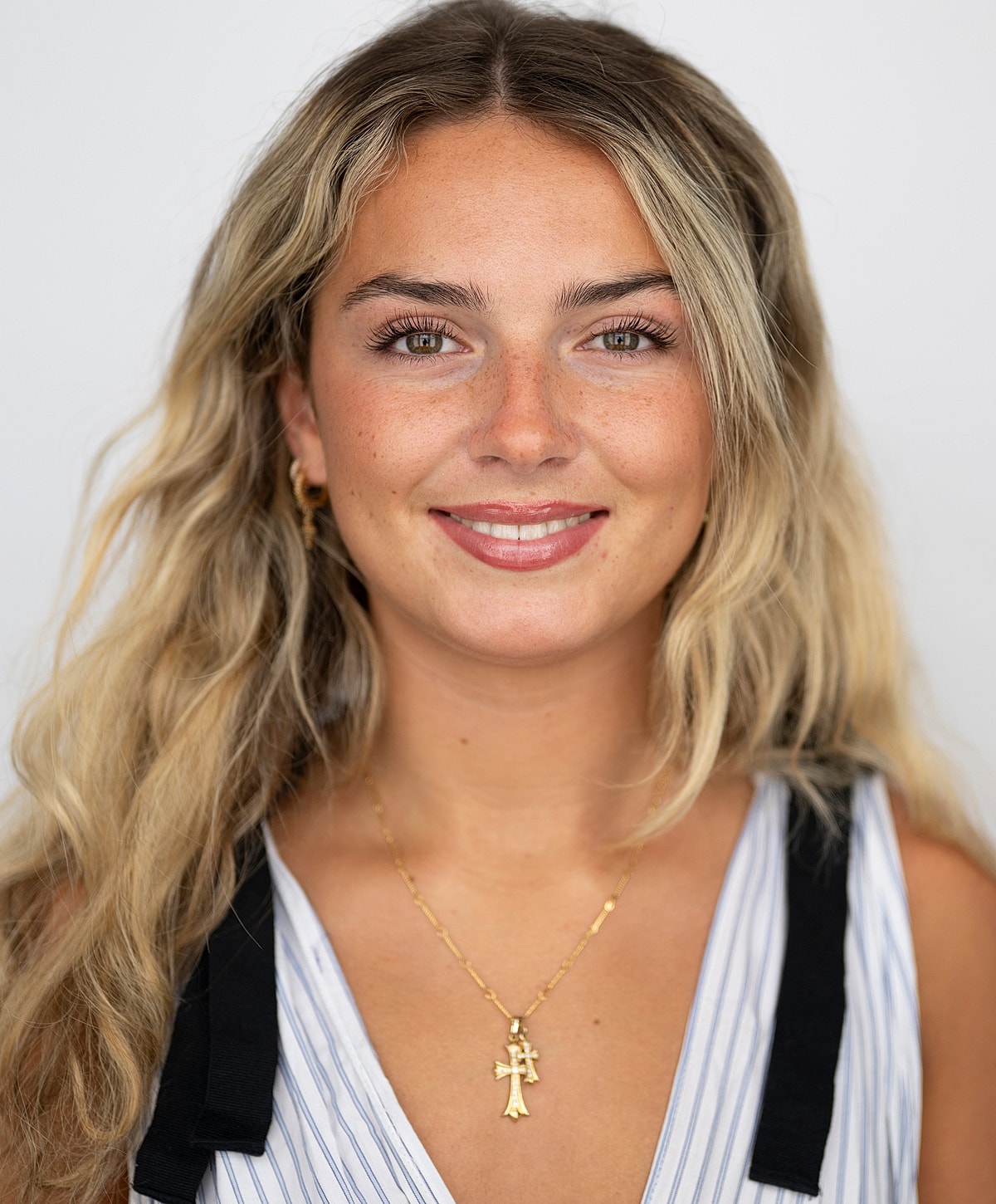 Smiling woman with wavy hair and necklace.